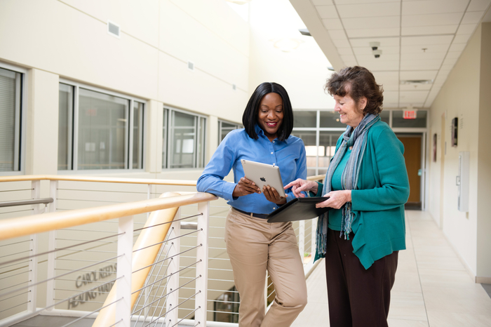 Two female professionals conferring about information on a computer tablet.