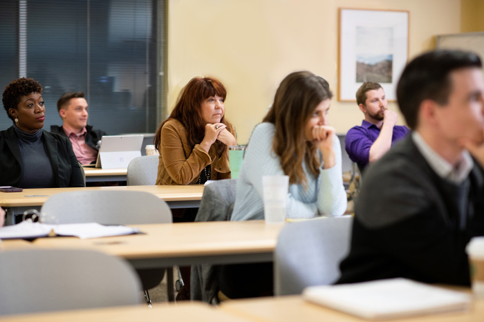 Graduate students sitting in classroom listening to instruction