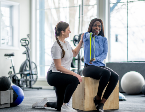 A Physical Therapist helps a woman missing an arm perform physical therapy exercises.