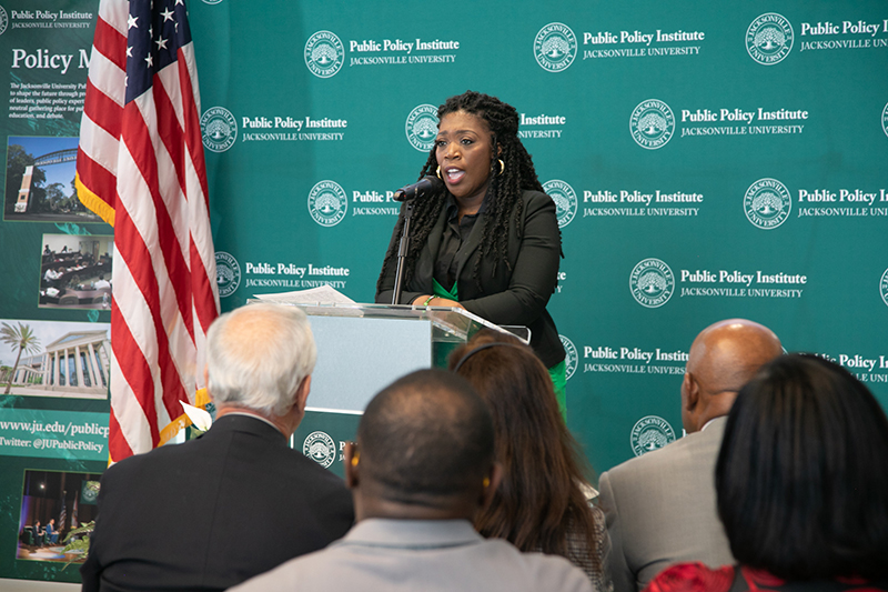 Woman speaking to a crowd at a podium