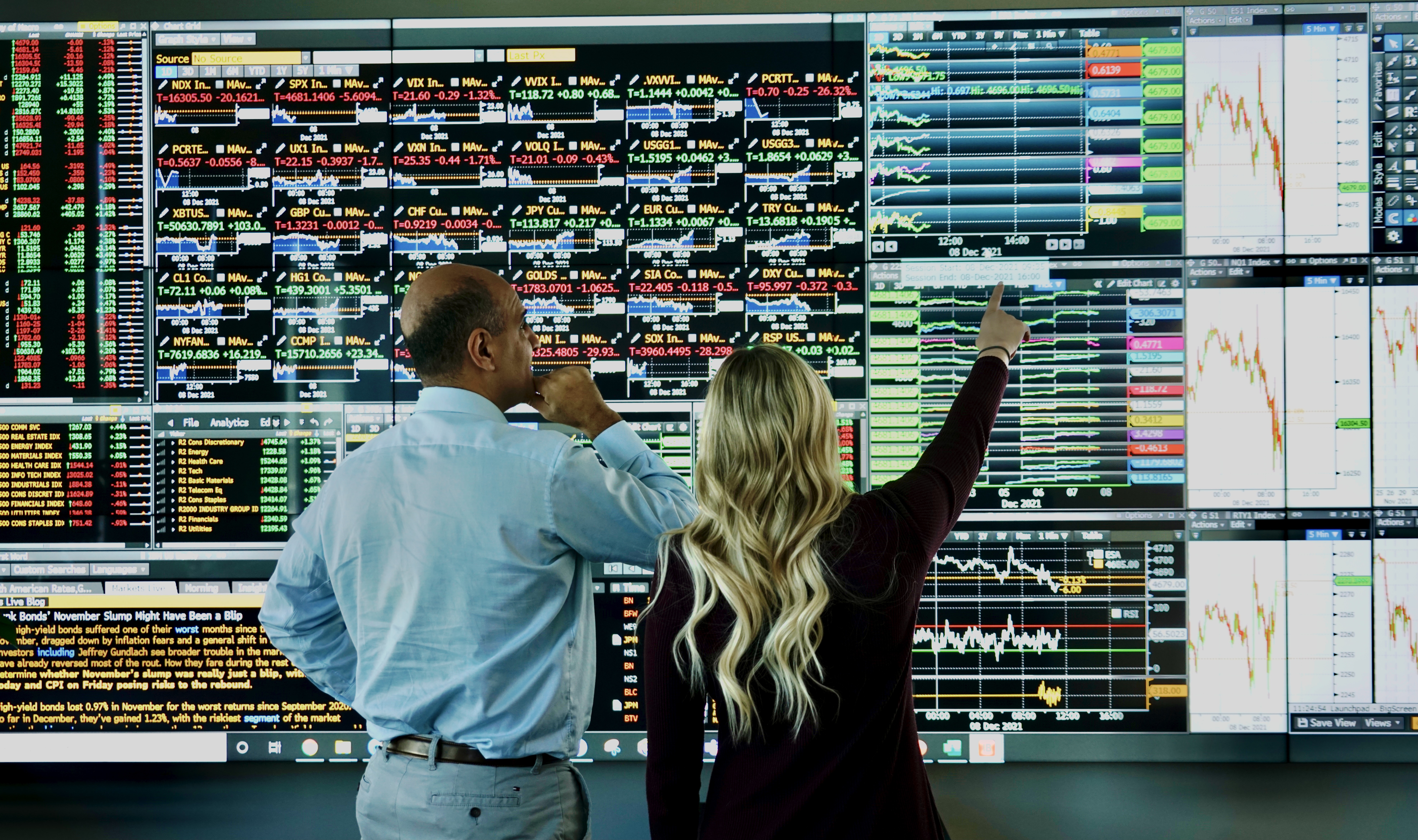 A student and professor reviewing stock analytics on a video board.