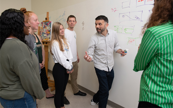 A studio classroom at Jacksonville University featuring students and a professor mapping graphic novels and children’s books.