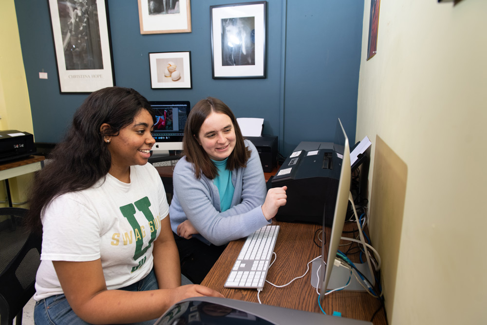 Two students reviewing photographs in Lightroom at an iMac in the digital Lab