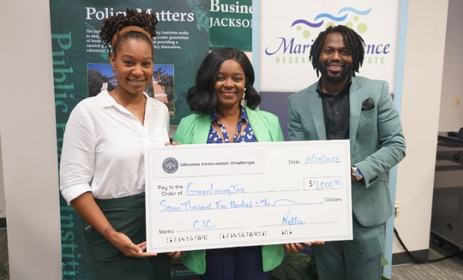 Three challenge participants holding a big check and smiling.