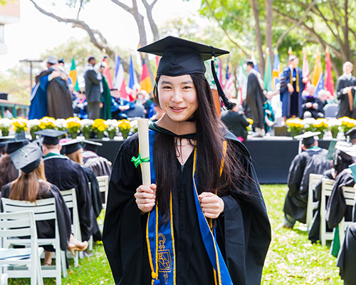 A student returning to her seat after receiving her diploma at graduation.