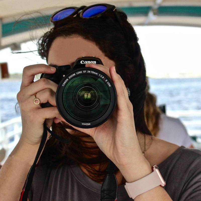 Front view of a student looking through the lens of her camera.