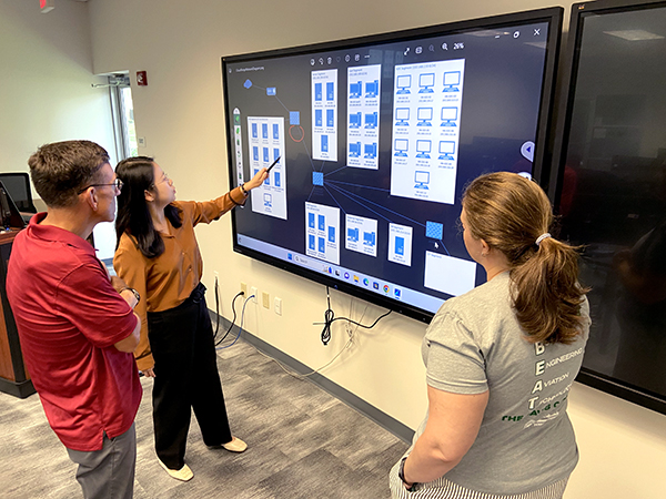 Cyber Range classroom with professor and two students.