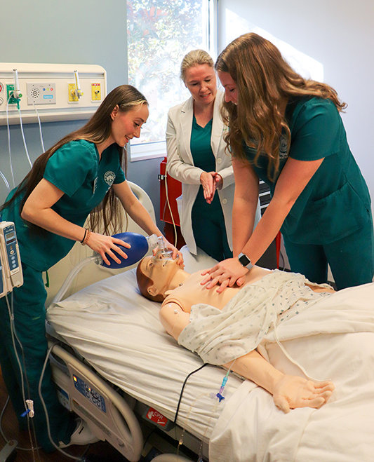 A nurse student holding an oxygen mask during a training simulation with a trainer.