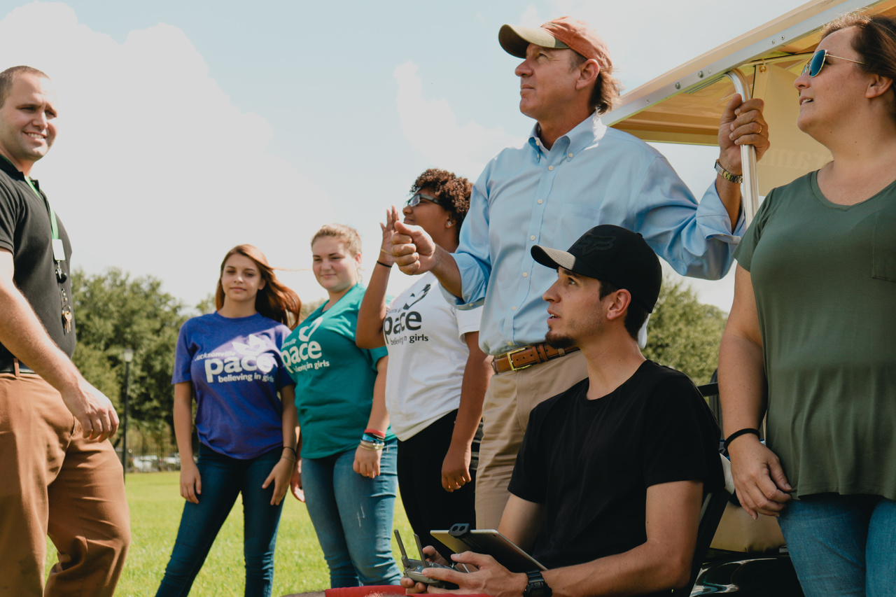 Male and female students learning aviation outside with male faculty member