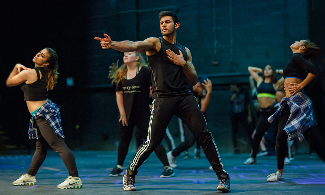 Students and choreography instructor on stage performing a Broadway style dance routine