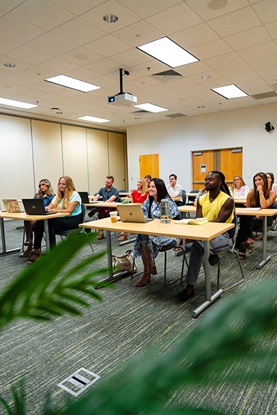 A group of students sits in a lecture hall and listens to instruction.