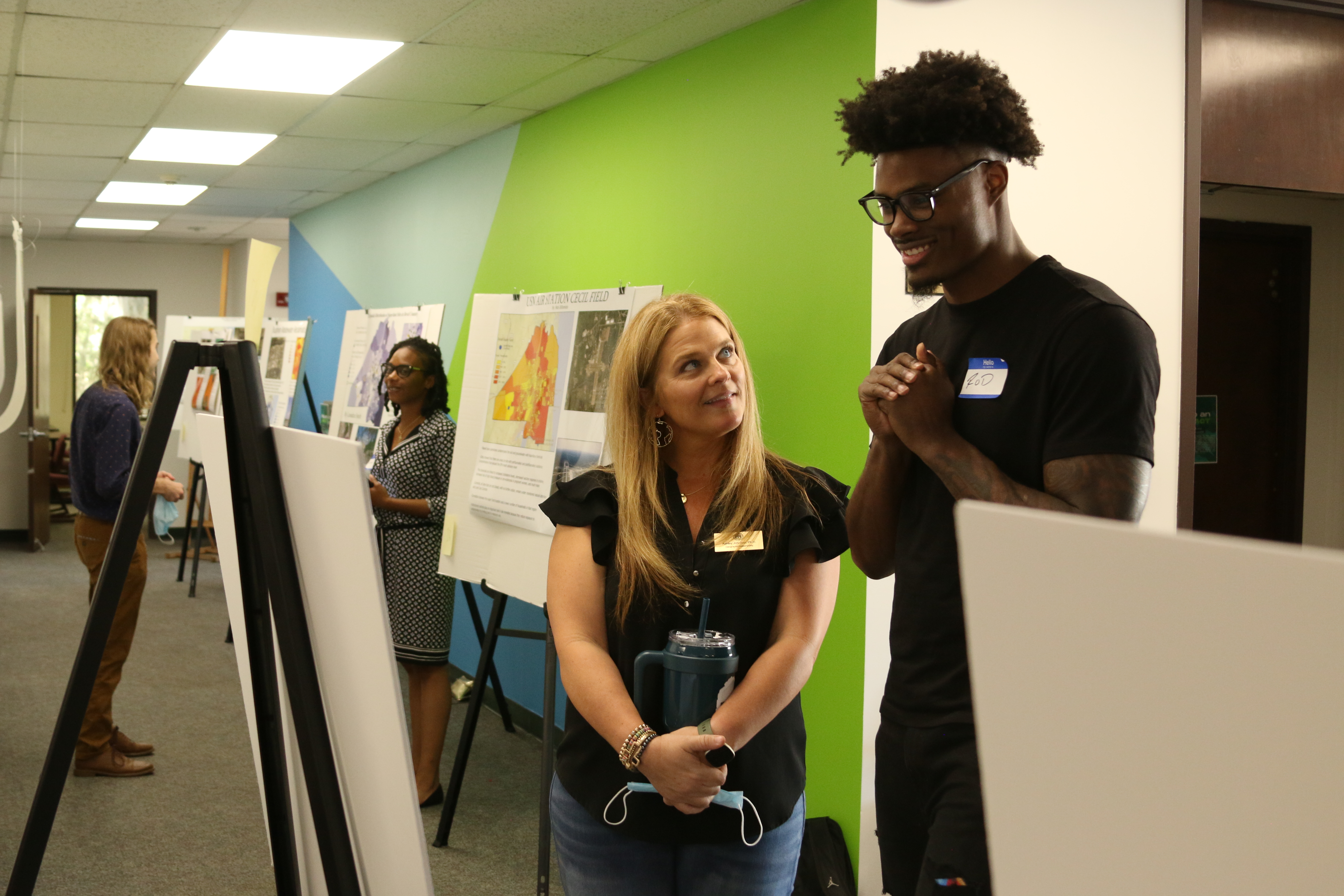 Dr. Ashley Johnson and male student looking at a map together in front of a colorful green and blue wall.