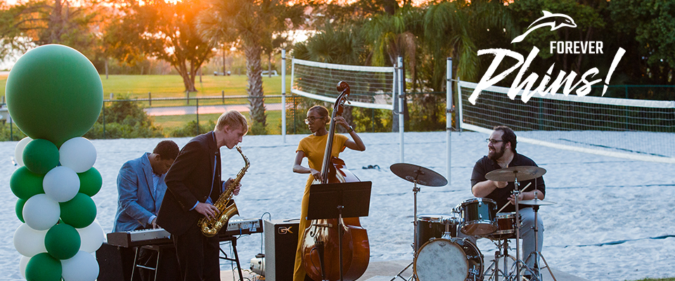 Photo of a band playing on a voleyball sand field.