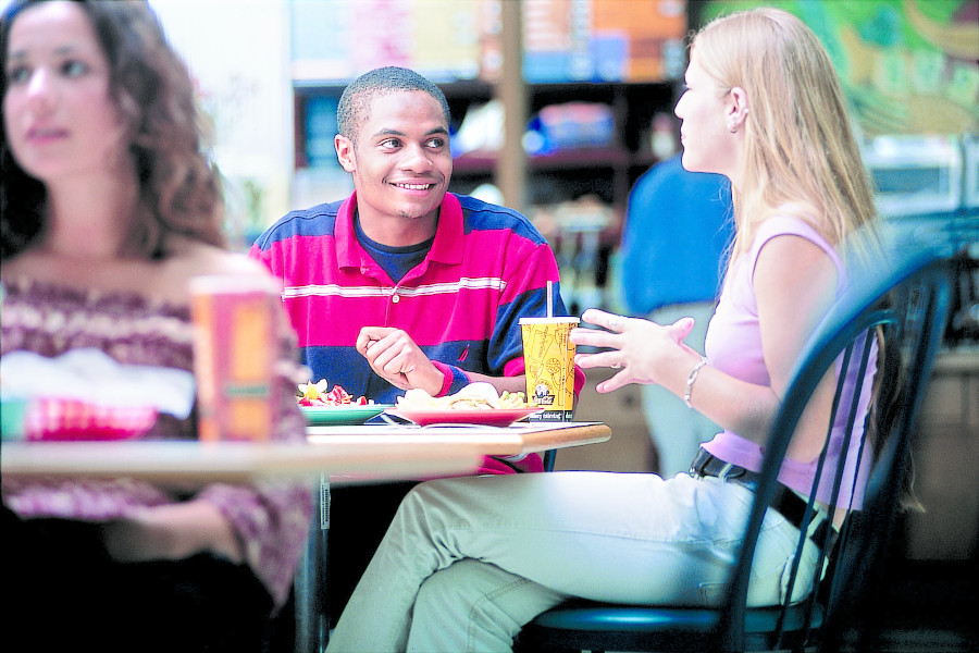 Students seating at a cafeteria table.