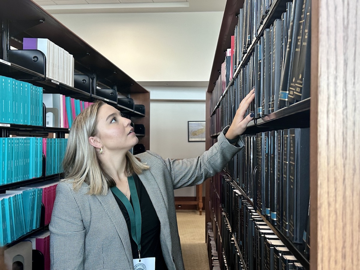 A female student reaching for a book in a courthouse library.