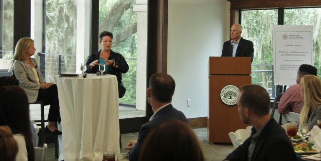 Speakers sit at table and talk to students and audience