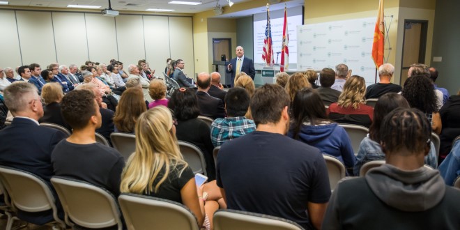 large audience looks at male speaker in front of room