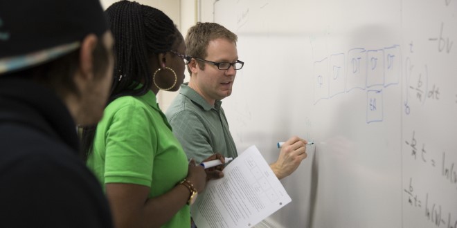 Professor Dr. Brian Lane teaching at the white board during class. 