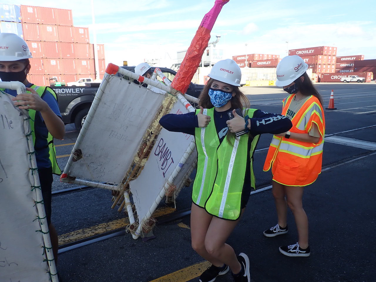 JU students posing with created "drifters" while on the dock in front of a Crowley maritime vessel