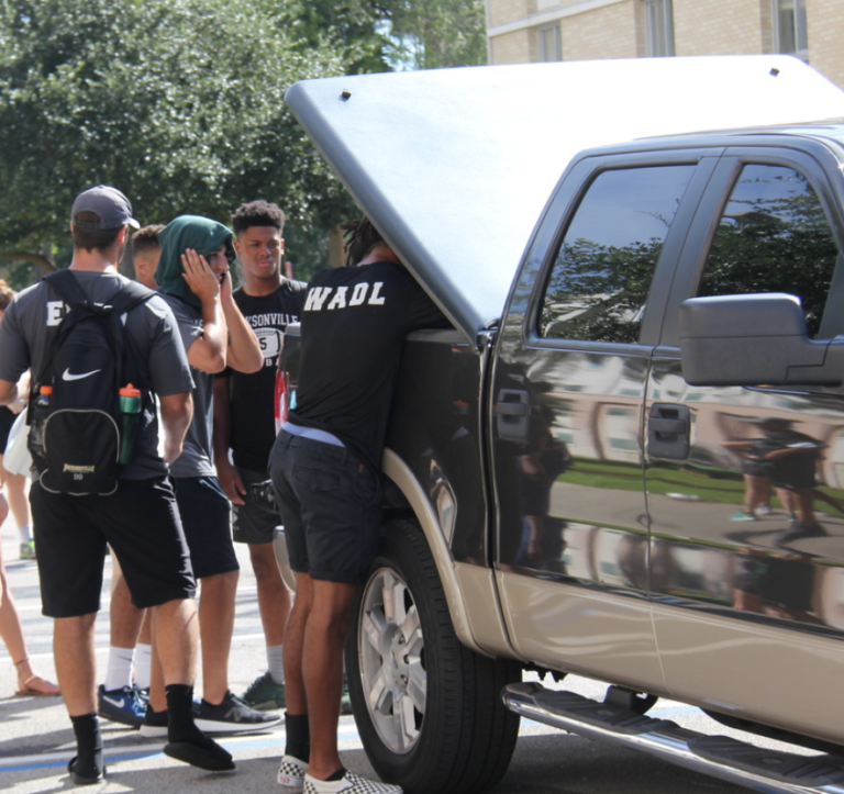 College kids standing at the back of a truck unpacking its contents