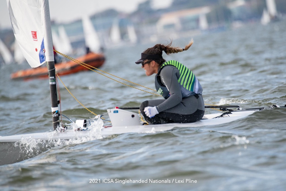 A female sailor steering a boat while smiling.