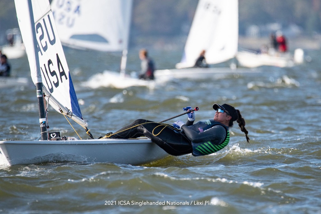 A female sailor leaning over the side of a sailboat.