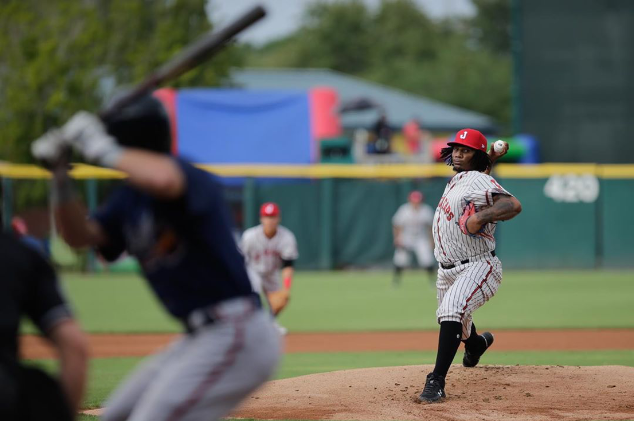 Action shot of a Jacksonville Jumbo Shrimp pitcher throwing the ball at the batter who is out of focus in the left corner of the photo