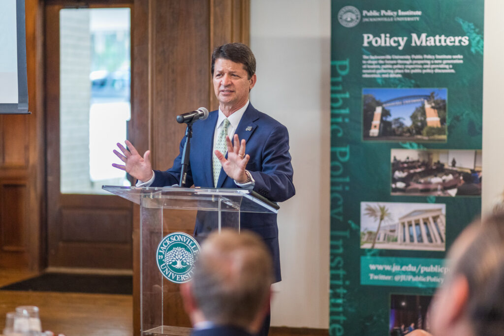 Mr. Mullaney talking with his hands in front of the public policy banner