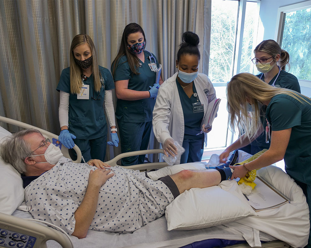 Nursing students work with a patient actor at JU.