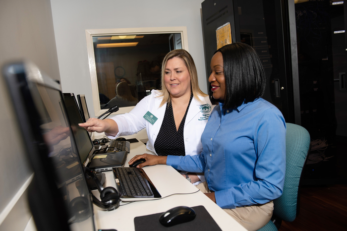 Nursing instructor and students checking information on a computer screen.