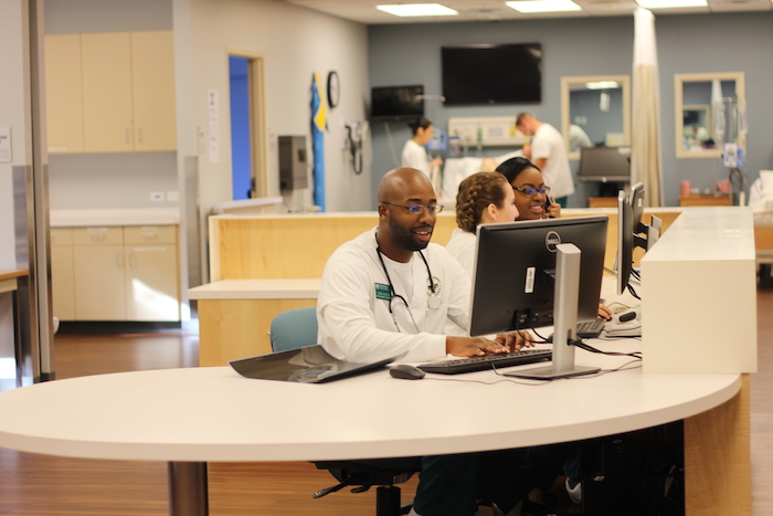 A nursing professional reviewing data at a computer.