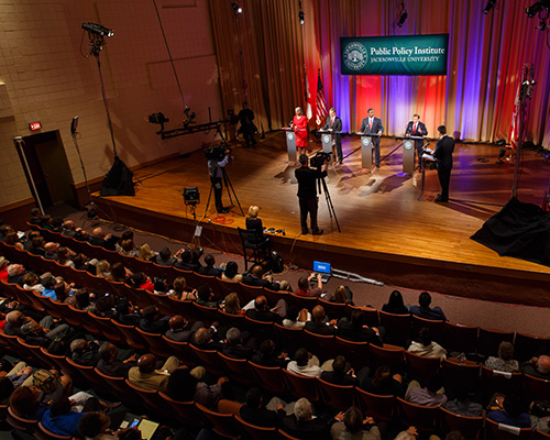 Political candidates on stage during a televised debate at Jacksonville University.