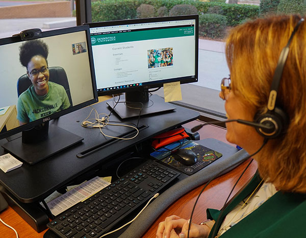 An advisor works with a student using a video chat over the computer.